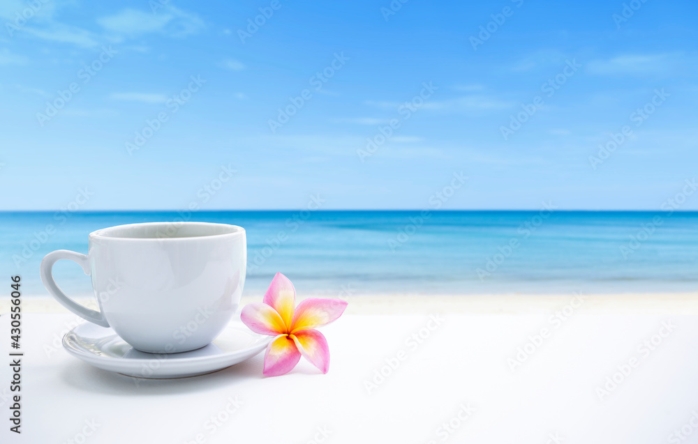 White coffee cup and plumeria flower on the beach, relaxing by the sea, summer holiday, vacation time, outdoor day light White coffee cup and plumeria flower on the beach, relaxing by the sea, summer holiday, vacation time, outdoor day light