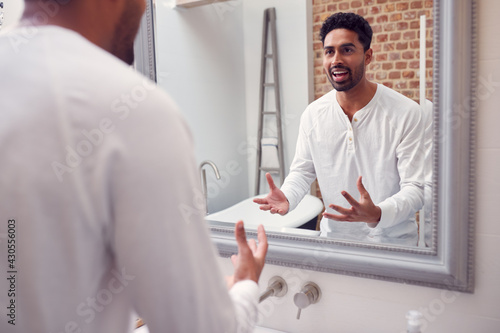 Fotografie Man At Home Practising Giving Speech Or Presentation In Bathroom Mirror