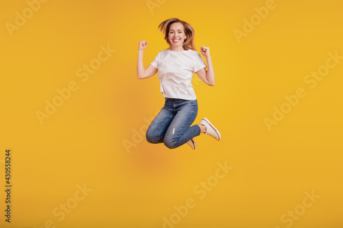 Smiling positive girl jumping active cheerful mood on yellow background
