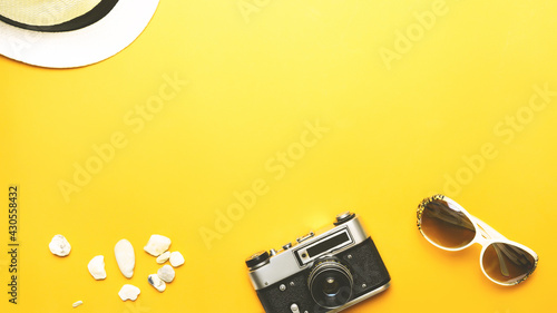 Summer vacation and travel concept. Beach accessories things - hat, sunglasses, camera, yellow backdrop. Summer is coming trendy concept. copy space