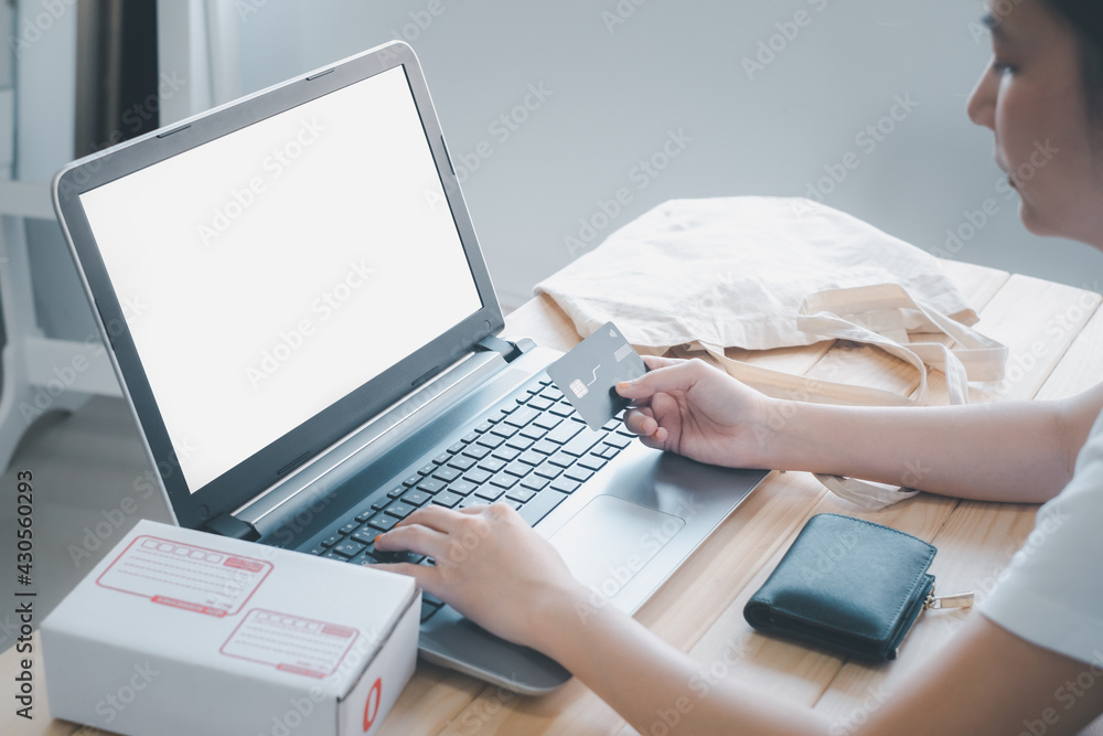 Woman hold credit card using laptop or computer notebook to shopping online and the shopping cart is ejected go out from the computer. She happy easy to buy and pay. Technology Shopping online concept Woman hold credit card using laptop or computer notebook to shopping online and the shopping cart is ejected go out from the computer. She happy easy to buy and pay. Technology Shopping online concept