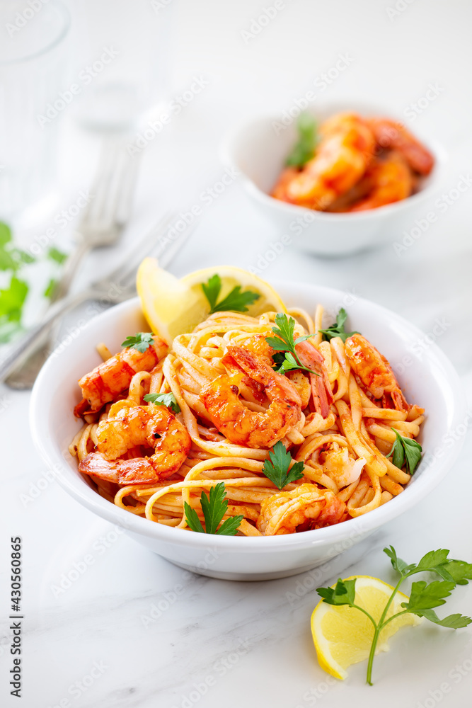 Spaghetti with shrimps or prawns garnished ith lemon and parsley leaves in a white bowl Spaghetti with shrimps or prawns garnished ith lemon and parsley leaves in a white bowl