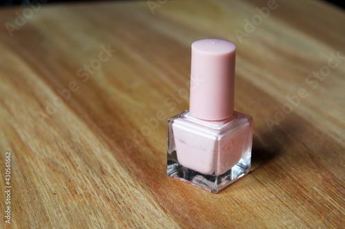 A tube of pink nail polish on a wooden background