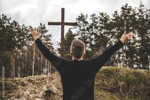 The man raised his hands and praises God. The man looks at the cross. Man believes in God. Hope in God