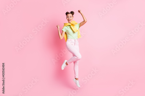 Photo of adorable lucky young lady dressed green t-shirt jumping high rising fists isolated pink color background