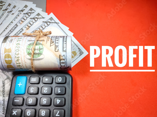 Business concept.Text PROFIT with calculator and banknote on red background.