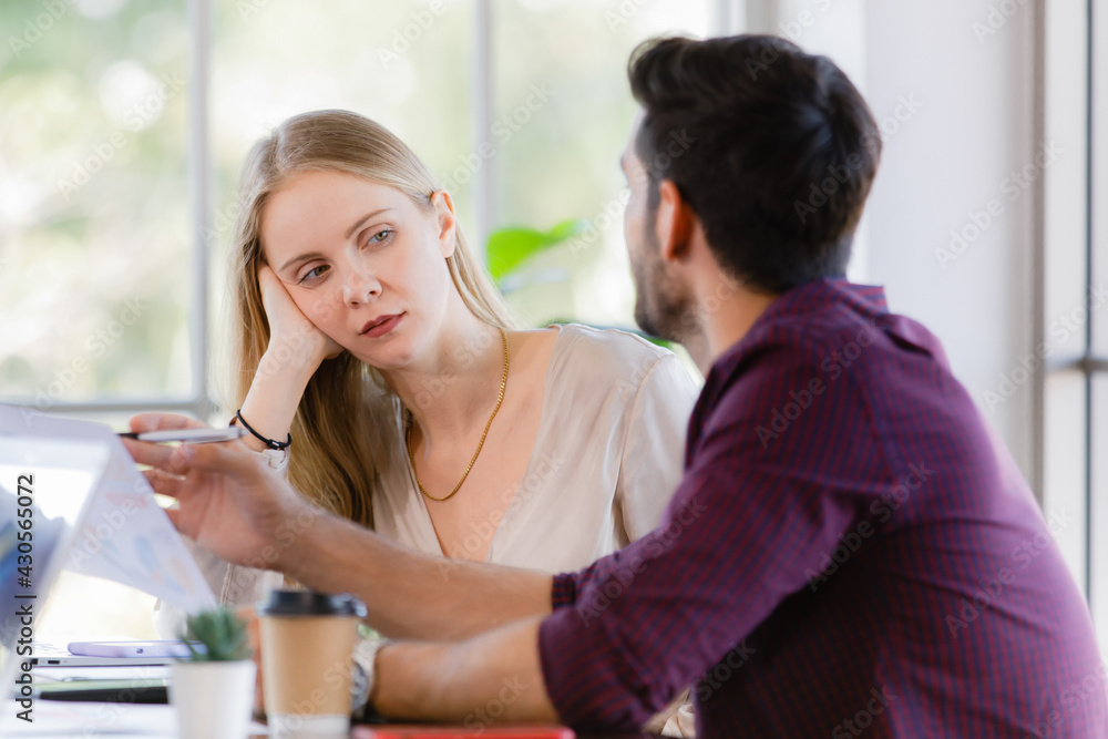 Two businesspeople, man and woman, working together in a modern office in an intimate manner. Idea for teamwork and good business colleagues Two businesspeople, man and woman, working together in a modern office in an intimate manner. Idea for teamwork and good business colleagues