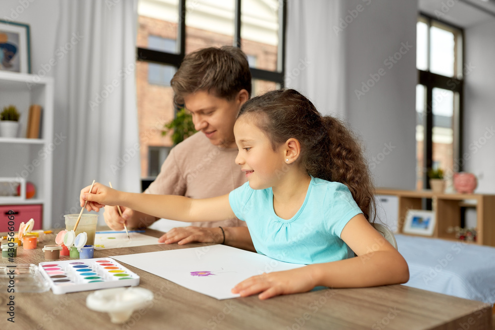 family, motherhood and leisure concept - happy smiling father spending time with his little daughter and drawing with colors at home family, motherhood and leisure concept - happy smiling father spending time with his little daughter and drawing with colors at home