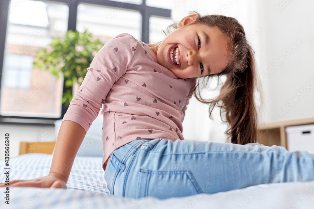 Portrait Of Happy Little Girl Sitting On Bed With Legs Crossed Kid