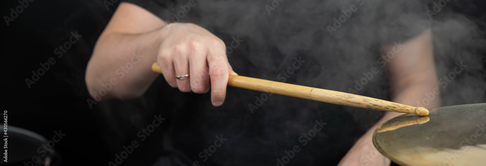 Fototapeta premium Professional drum set closeup panorama banner. Man drummer with drumsticks playing drums and cymbals, on the live music rock concert or in recording studio