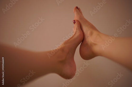 female legs with feet to each other on beige wall background