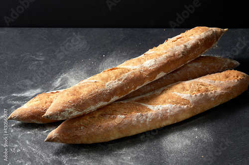 food, baking and cooking concept - pile of baguette bread on table over dark background