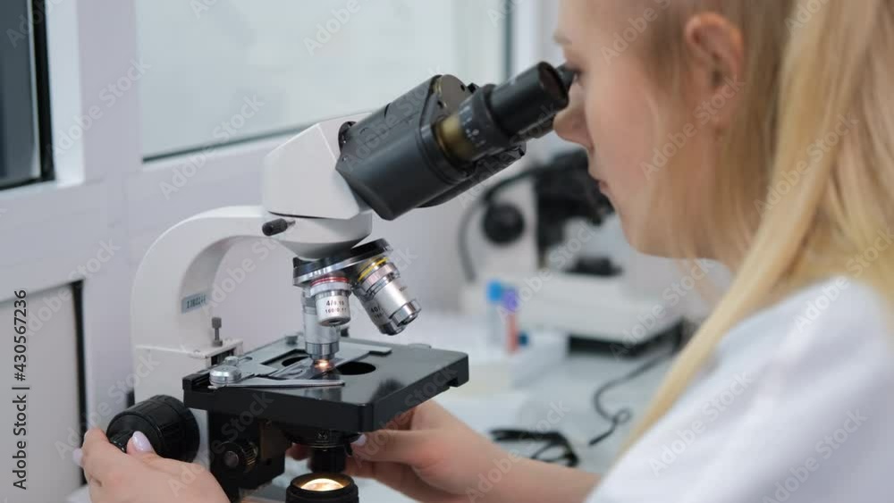 Female Researcher Worker Making Blood Test for Detection of Antibodies and Infections in a Lab. Looking Through a Microscope. Concept of Science and Medical Healthcare Technology Female Researcher Worker Making Blood Test for Detection of Antibodies and Infections in a Lab. Looking Through a Microscope. Concept of Science and Medical Healthcare Technology