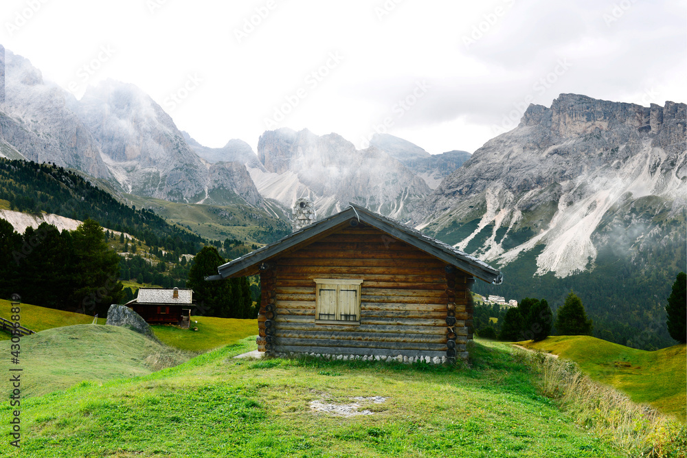 Old wooden shelters in Dolomites mountain. In the background Sassolungo peak.