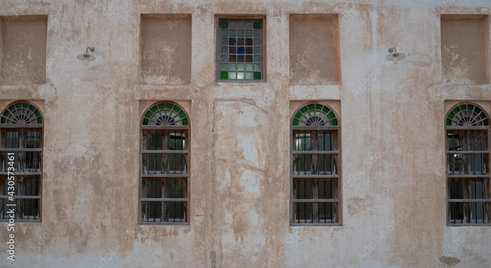 Front view of an Arabic old wall with traditional wooden windows and door in Qatar.