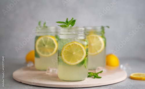 three Lemon mojito cocktail with mint in mason jars on top of wood. lemon mojito