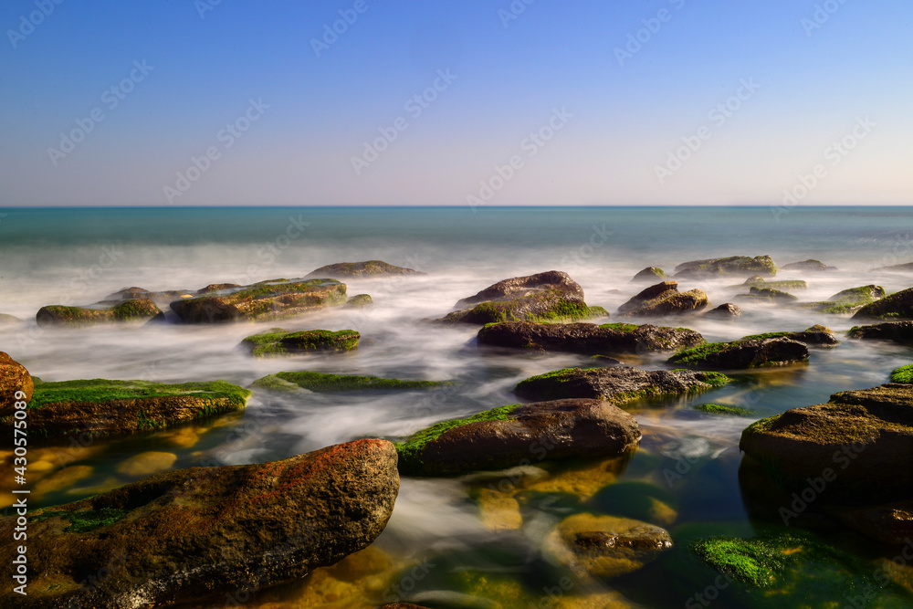 Long exposure by the sea. Waves break against stones. 