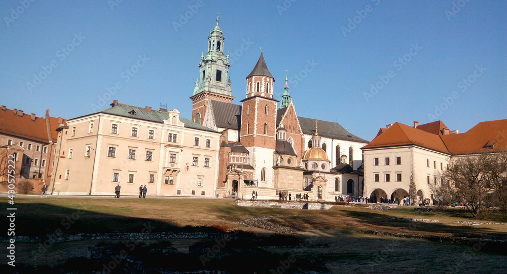 Entrance to the castle. Couple walking on the street. Scenic view of the old town country on a sunny day. Beautiful scape with medieval castle. Group of young people sightseeing famous Krakow landmark