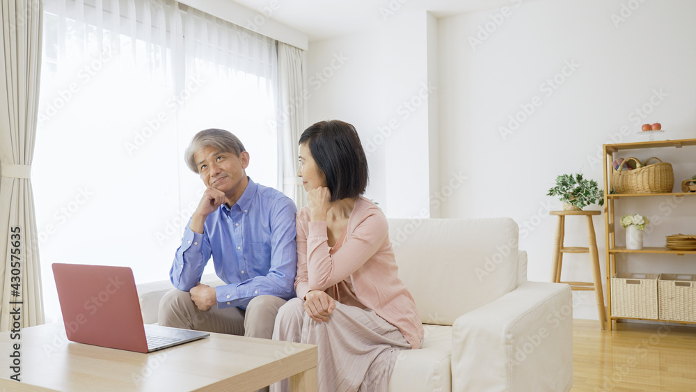 パソコンをしながら考え事をする中高年夫婦 パソコンをしながら考え事をする中高年夫婦