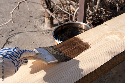 Painting a wooden board outdoors. Coated with protective oil against decay and moisture. photo