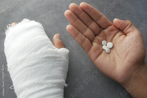 injured painful hand with bandage and medical pills on hand 
