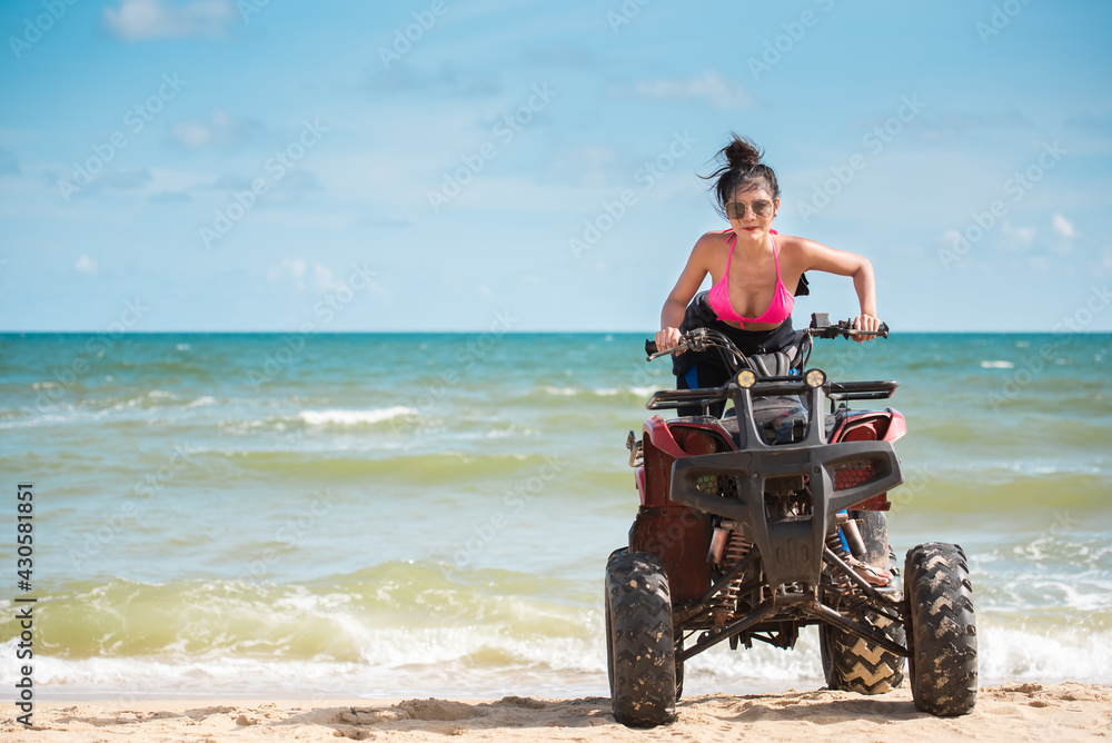 Asian young beautiful woman model in a bikini pose with ATV bike at the beach.summer vacation.