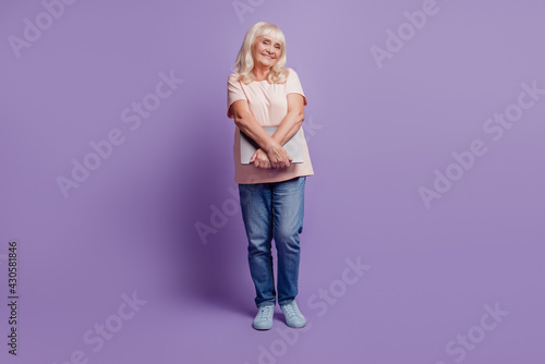 Beautiful old woman carry laptop on purple background