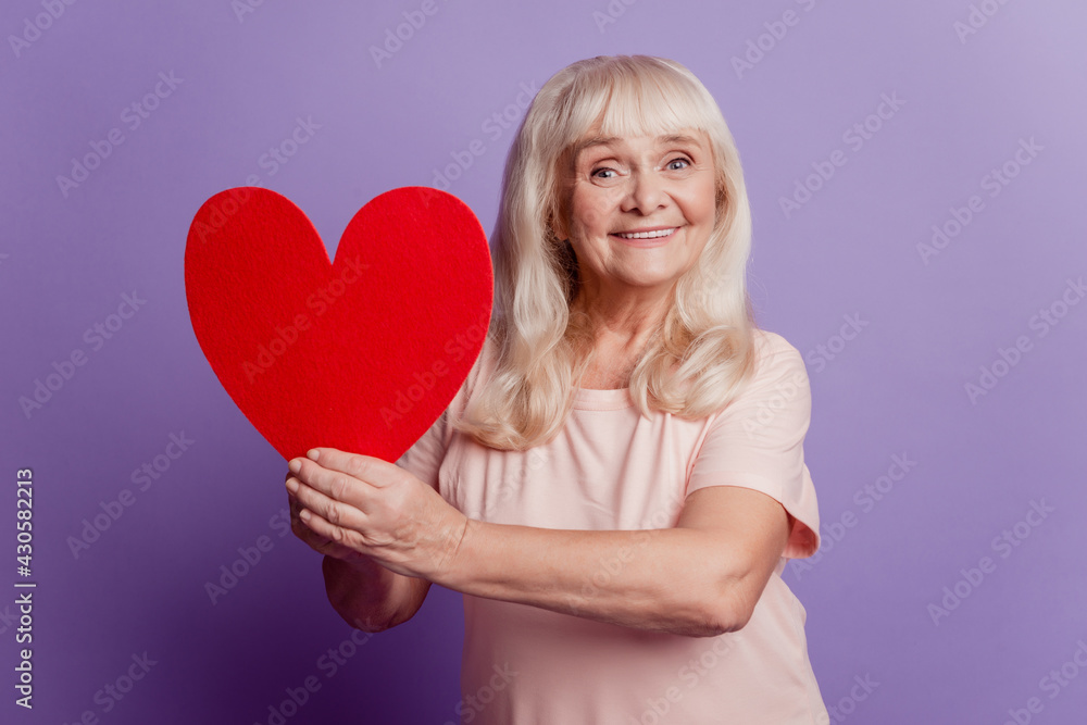Photo of elderly woman hold big valentine card heart isolated on violet background Photo of elderly woman hold big valentine card heart isolated on violet background