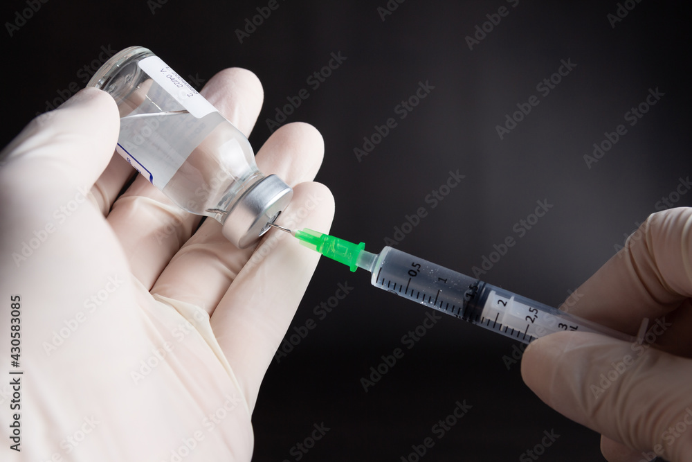 Medicine on the left being aspirated into a syringe on dark background Medicine on the left being aspirated into a syringe on dark background