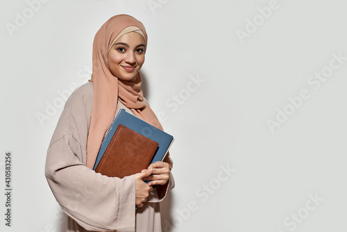 Smiling young arabian woman in hijab with copybook photo