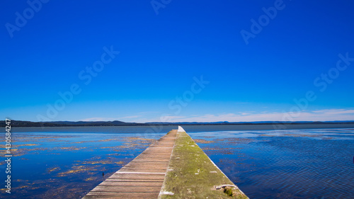Scenic view of a long jetty in Tuggerah lake under a clear blue sky photo
