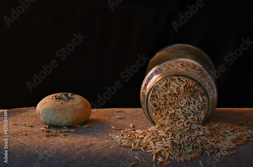 Still life in warm light with grains,  jar and bun