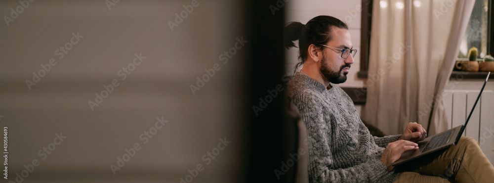 A man is working or watching a video at his home workplace in the evening A man is working or watching a video at his home workplace in the evening