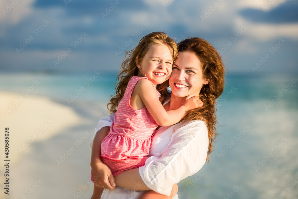 Portrait of happy mother and little daughter on sunny beach on Maldives at summer vacation Portrait of happy mother and little daughter on sunny beach on Maldives at summer vacation