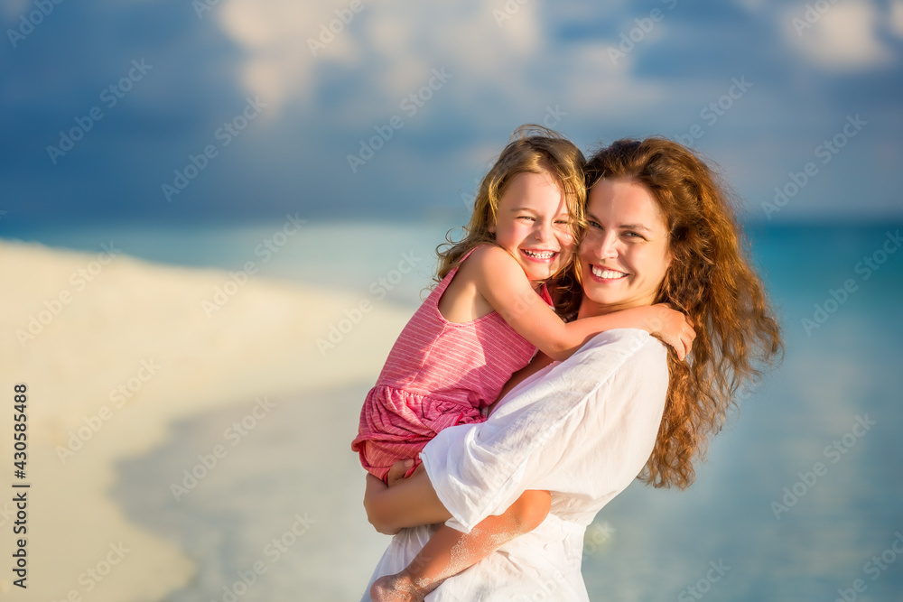 Portrait of happy mother and little daughter on sunny beach on Maldives at summer vacation Portrait of happy mother and little daughter on sunny beach on Maldives at summer vacation
