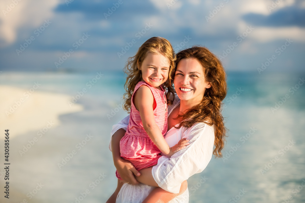 Portrait of happy mother and little daughter on sunny beach on Maldives at summer vacation Portrait of happy mother and little daughter on sunny beach on Maldives at summer vacation