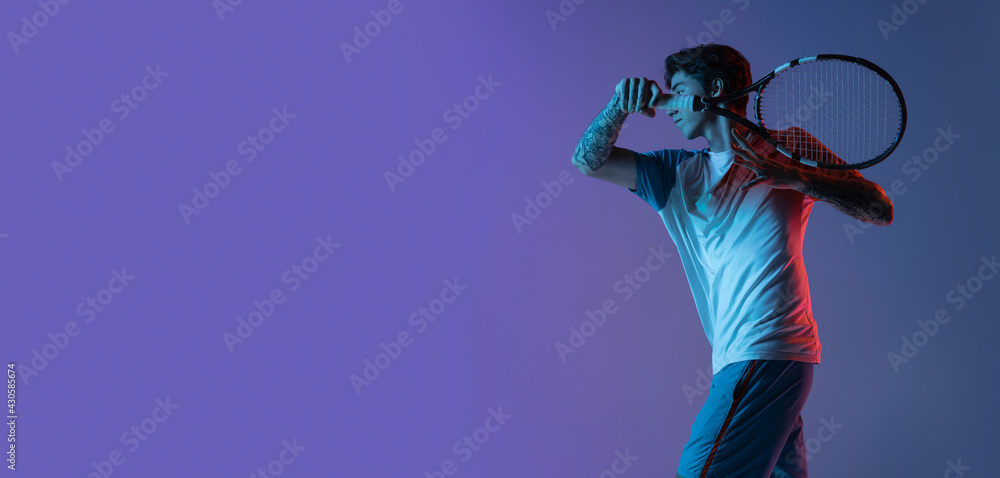 Young caucasian man playing tennis isolated on purple-blue studio background in neon, action and motion concept Young caucasian man playing tennis isolated on purple-blue studio background in neon, action and motion concept