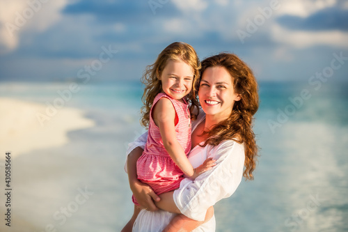 Portrait of happy mother and little daughter on sunny beach on Maldives at summer vacation