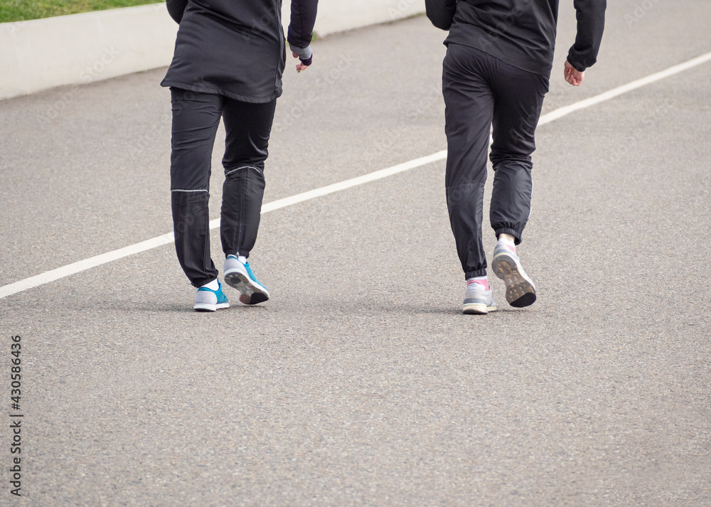 Speed walking. Lower body parts of people running on asphalt track. Speed walking. Lower body parts of people running on asphalt track.