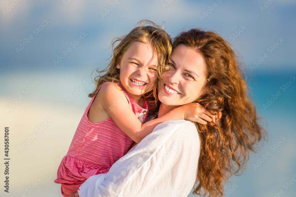 Portrait of happy mother and little daughter on sunny beach on Maldives at summer vacation Portrait of happy mother and little daughter on sunny beach on Maldives at summer vacation