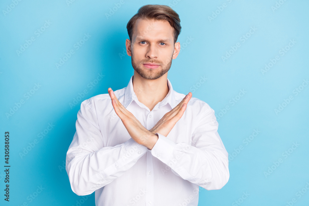 Portrait of attractive serious guy showing stop sign crossed hands isolated over bright blue color background Portrait of attractive serious guy showing stop sign crossed hands isolated over bright blue color background