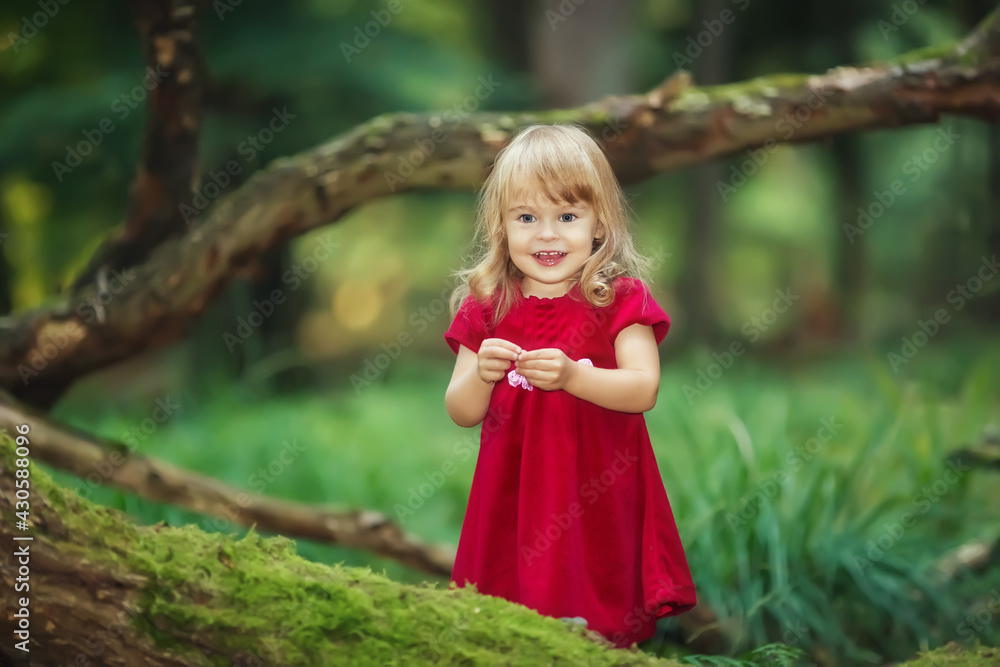 Little girl in the wild green forest