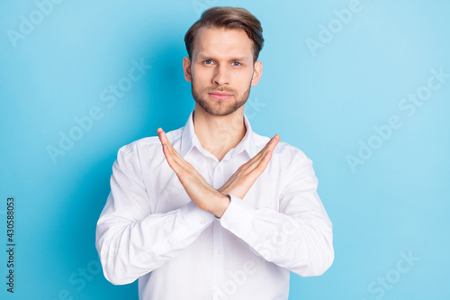 Portrait of attractive serious guy showing stop sign crossed hands isolated over bright blue color background © deagreez
