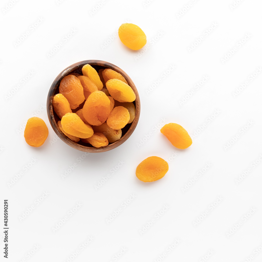 Top down view of a wooden bowl filled with dried apricots isolated against a white background. Top down view of a wooden bowl filled with dried apricots isolated against a white background.