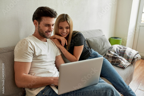 Young couple watching something funny on laptop and chilling