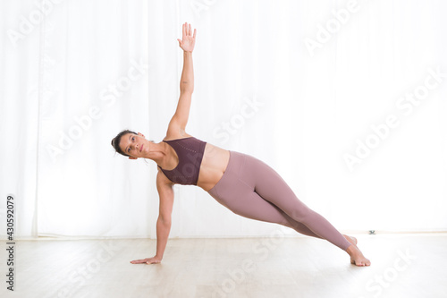 Portrait of active sporty young woman practicing yoga in studio. Healthy active lifestyle, working out indoors in gym photo