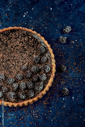Chocolate tart with blackberries over dark blue background