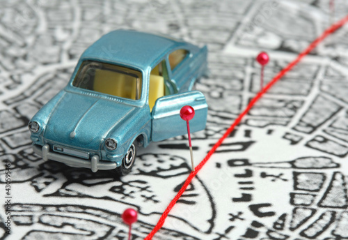 City map, route marked with safety pins. The blue toy car stands with the door open. Concept: travel along the route, stopover, destination, goal.