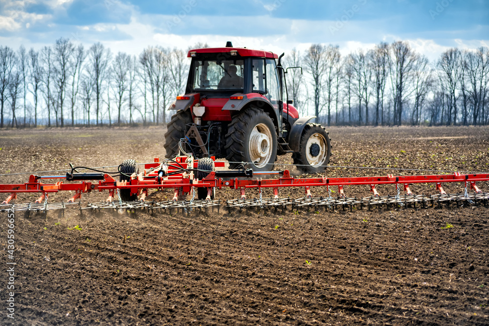 Obraz premium tillage in the field with a tractor with a trailed machine