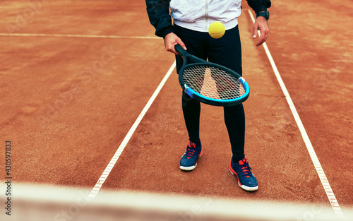 Cropped shot of young man bounces the ball on the racket, during playing tennis on the court. Male tennis player practicing outdoors. © iuricazac